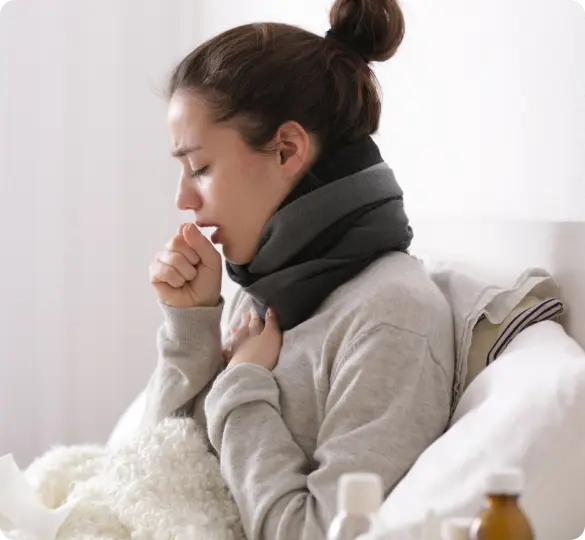 View of sick woman coughing in bed.
