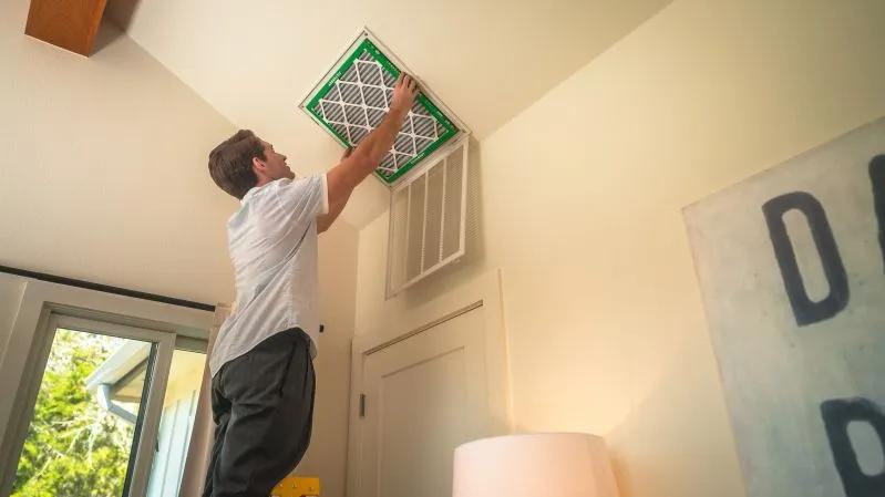 A view of a homeowner replacing an HVAC air filter at home.