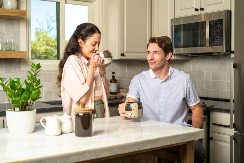 How to Cut a Size-to-Fit AC Air Filter - Image of a couple sitting at a kitchen counter, enjoying coffee together while smiling at each other, surrounded by kitchen plants and appliances.