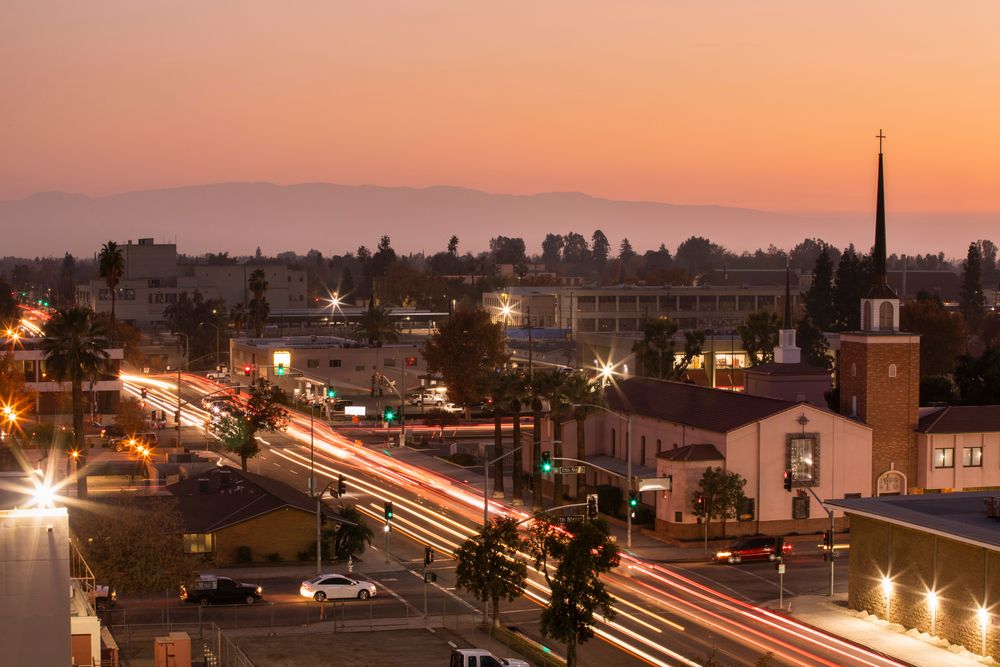 San Bernardino cityscape at dusk with light trails and mountain backdrop.