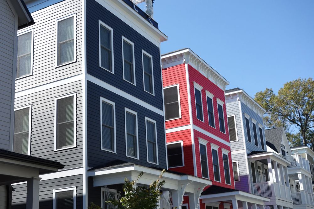 Row of colorful modern townhomes under clear blue sky.