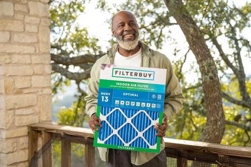 View of smiling man holding a Filterbuy indoor air filter on a balcony, showcasing the best 8x20x2 air filter for home
