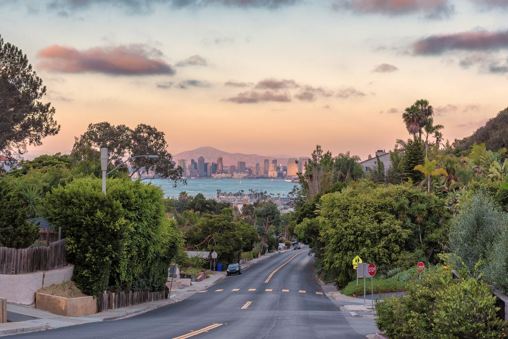 Residential street in San Diego with a view of downtown skyline at sunset.