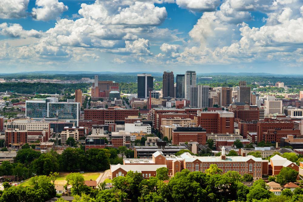 Scenic view of downtown Birmingham, Alabama skyline with modern buildings and dramatic clouds.