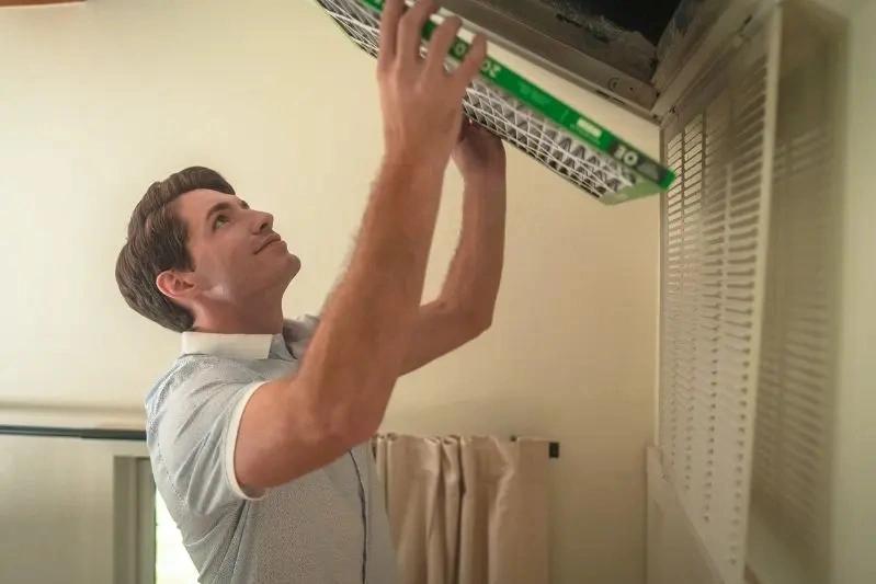 Bemis Humidifier Air Filter and Parts Replacement - Image of a man installing air filter at home.