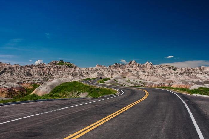 The Hottest City in Every State - Infographics of winding road through Badlands National Park near Interior, South Dakota and the hottest spot in the state, known for scorching sun and rugged beauty.