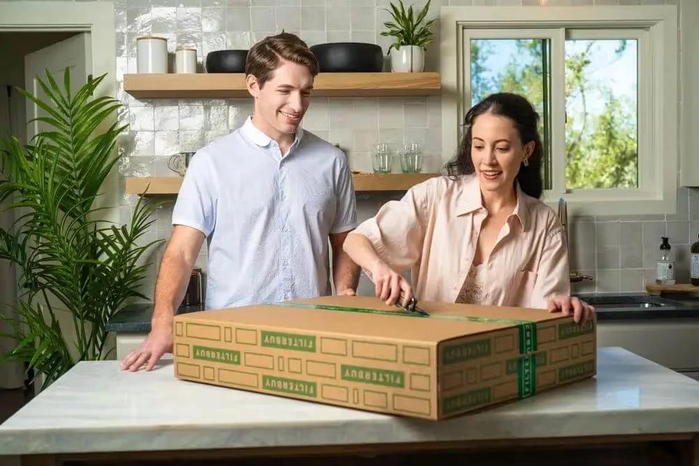 Couple unboxing a Filterbuy air filter delivery in a modern home kitchen.