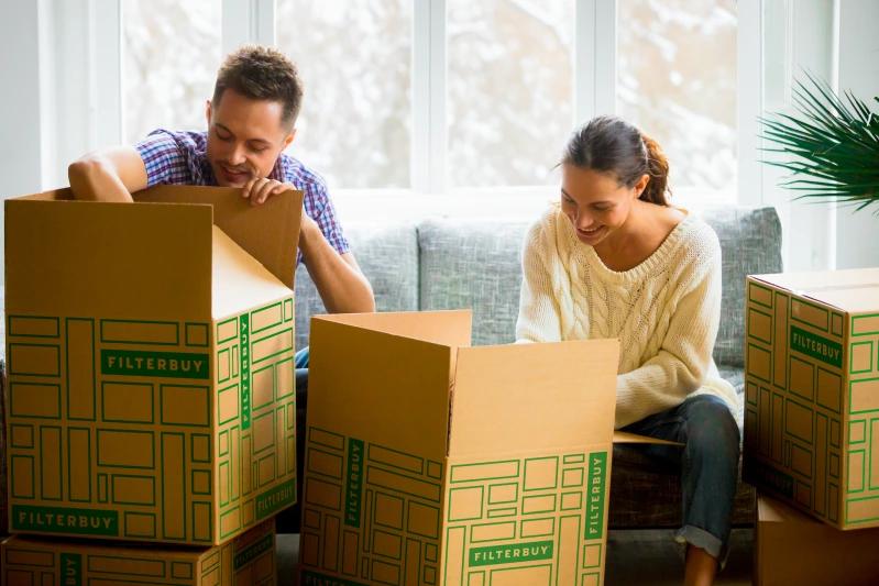 View of -  A  couple unpacks Filterbuy boxes in a cozy, snow-lit living room.
