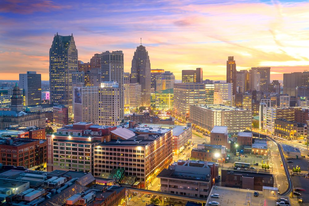 Downtown Detroit, Michigan skyline at dusk with vibrant lights and historic architecture.