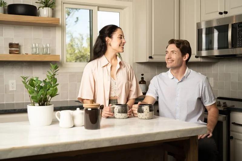 View of young couple enjoying fresh indoor air in a modern kitchen, enhanced by clean air quality, indoor plants, and effective air filters.