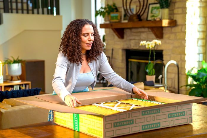 A view of a delighted homeowner unboxing a high-quality Bryant air filter from Filterbuy. 