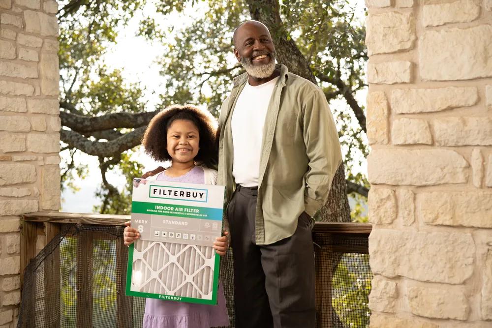 A view of a smiling child holding a 6x10x1 air filter beside an adult, representing top HEPA and MERV options for allergy relief and better indoor air quality.