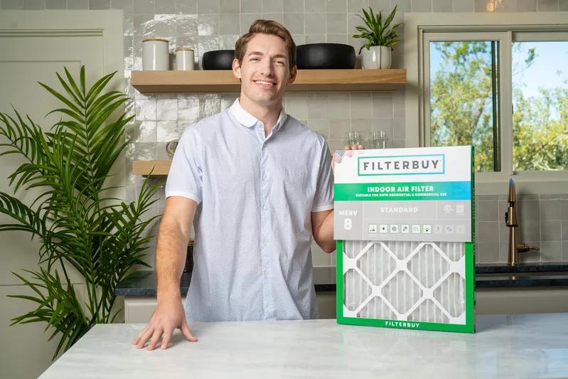 A view of a man in a modern kitchen holding a high-efficiency 10x10x4 air filter, showcasing its ability to improve indoor air quality and HVAC performance.