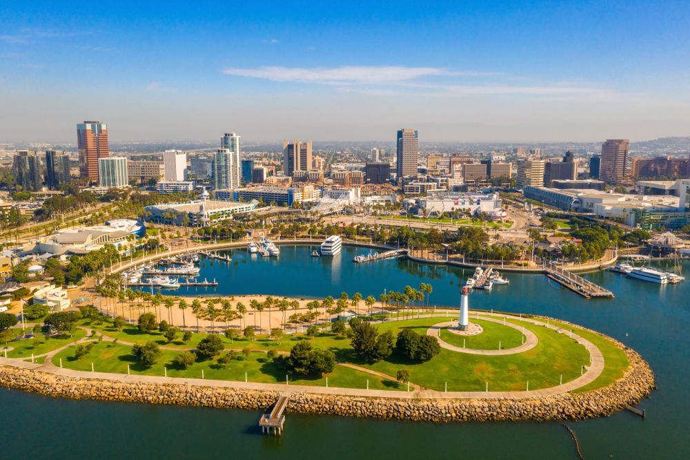  Aerial view of the harbor, lighthouse park, and downtown skyscrapers under a clear blue sky.