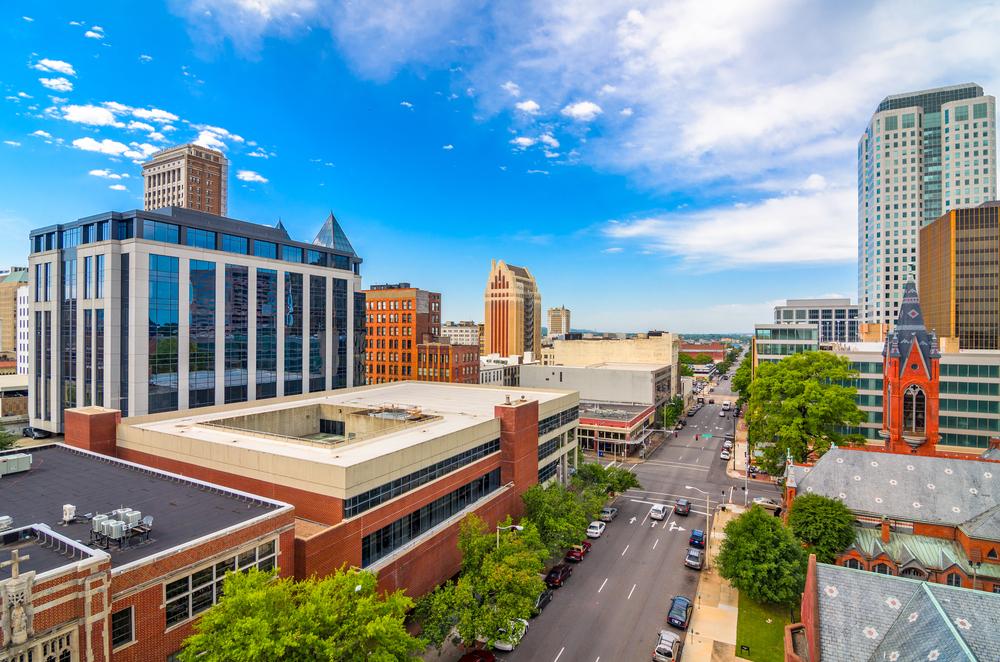 Downtown Birmingham, Alabama skyline with a mix of modern and historic architecture under a bright blue sky.