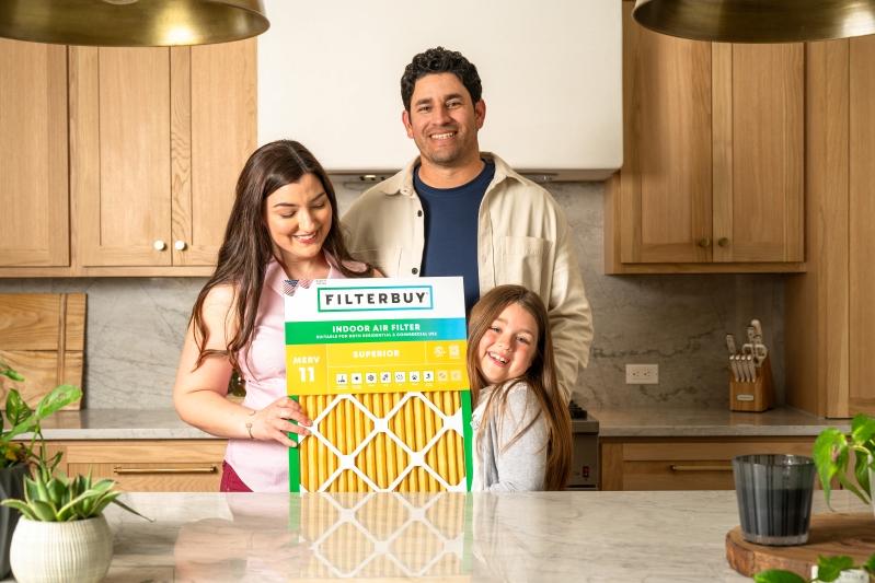 Flanders Company Replacement HVAC Air Filters - Image of a family standing together in a kitchen holding a Filterbuy MERV 11 air filter, smiling and ready to improve indoor air quality.
