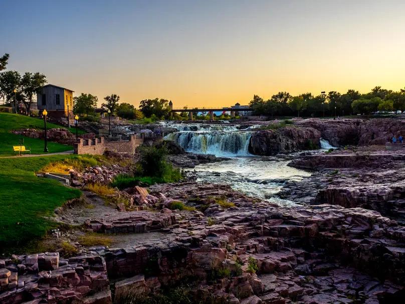 Image of waterfalls in South Dakota with beautiful rugged landscape and empty footwalks beside the river.