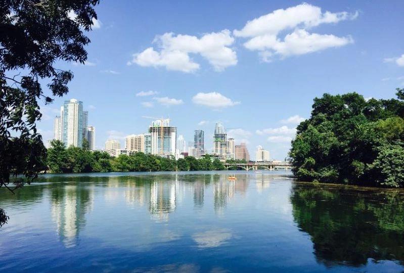 Cities Where Remote Workers Log the Most Hours - Images of the Austin, Texas skyline with a serene view of the river and trees, capturing a bright and clear day.