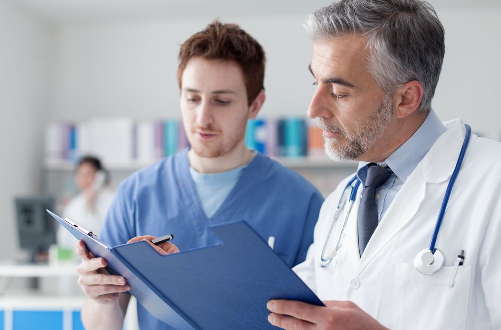 Two male doctors reviewing a patient chart together in a medical office.