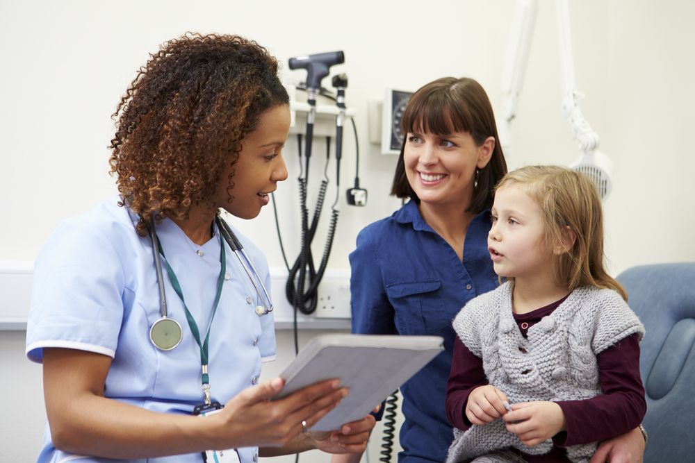 Female nurse or doctor talking to a mother and child during a clinic visit