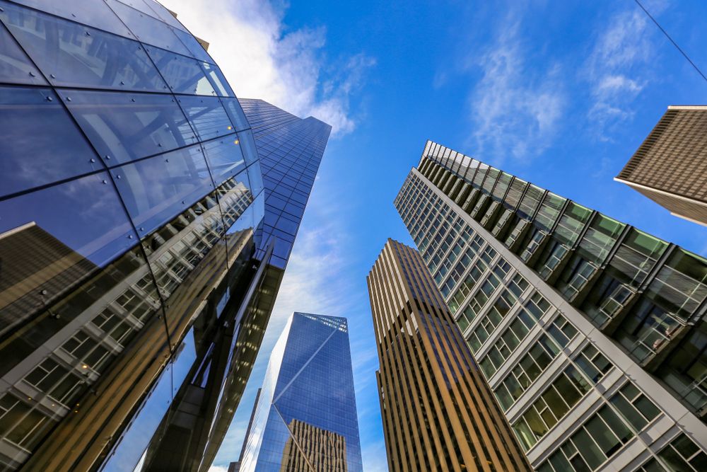 Looking up at modern skyscrapers reflecting the sky in a downtown cityscape