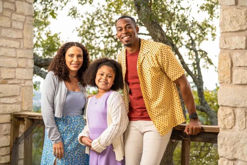View of smiling family posing on a scenic outdoor balcony with trees in the background