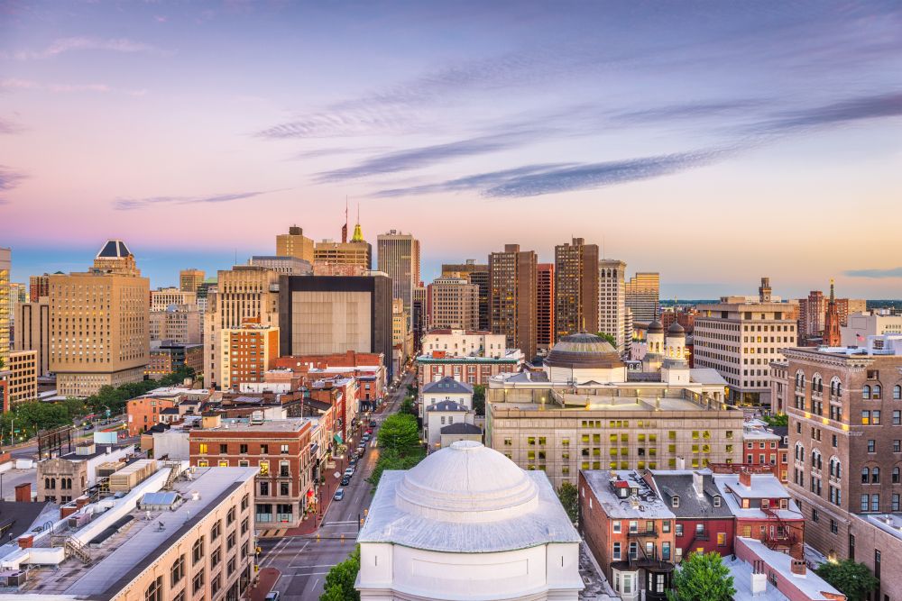 Cityscape of downtown Baltimore, Maryland at dusk with a colorful skyline and historic buildings