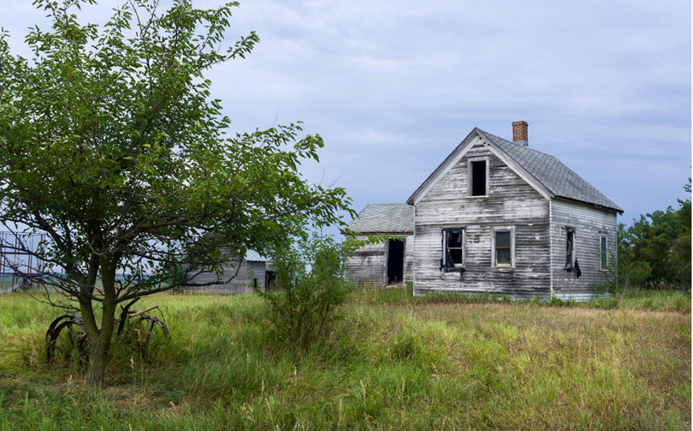 Large stone monument surrounded by buildings and traffic circle in city center at twilight.