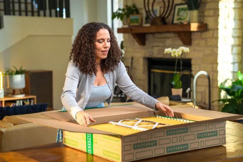 View of a woman opening Filterbuy HVAC and furnace air filter box in cozy living room
