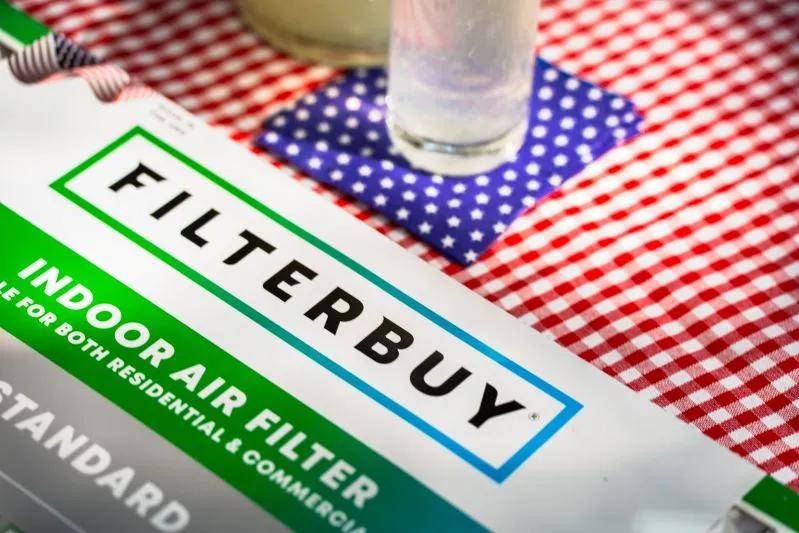 Best Air Purifier Replacement Filters - image of a Filterbuy air filter box on a red checkered tablecloth with a glass on a blue polka dot coaster.