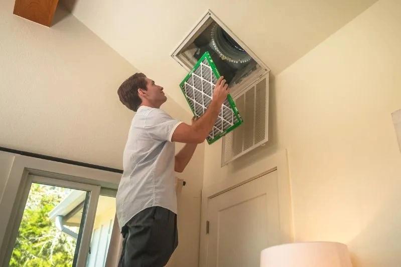 Replacement Range Hood Filters and How to Clean Grease Off - Image of a man installing his air filter.