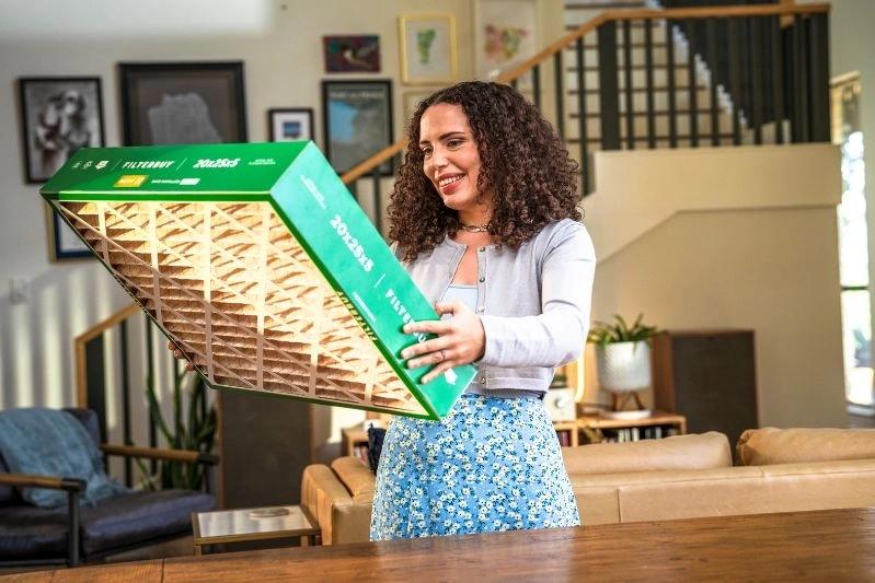Replacement Factory Direct HVAC Air Filters Near Me - Image of a woman smiling as she receives her order from Filterbuy.
