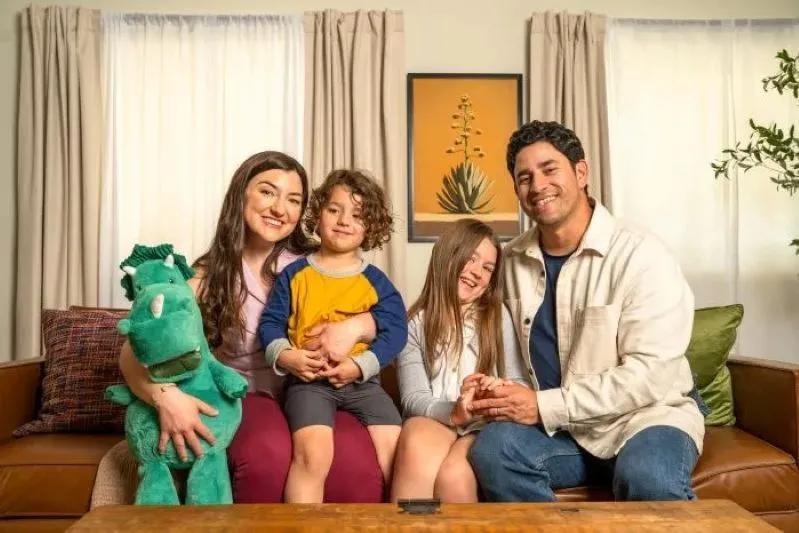 A view of a happy family sitting together on a couch in a cozy living room, smiling and enjoying quality time.