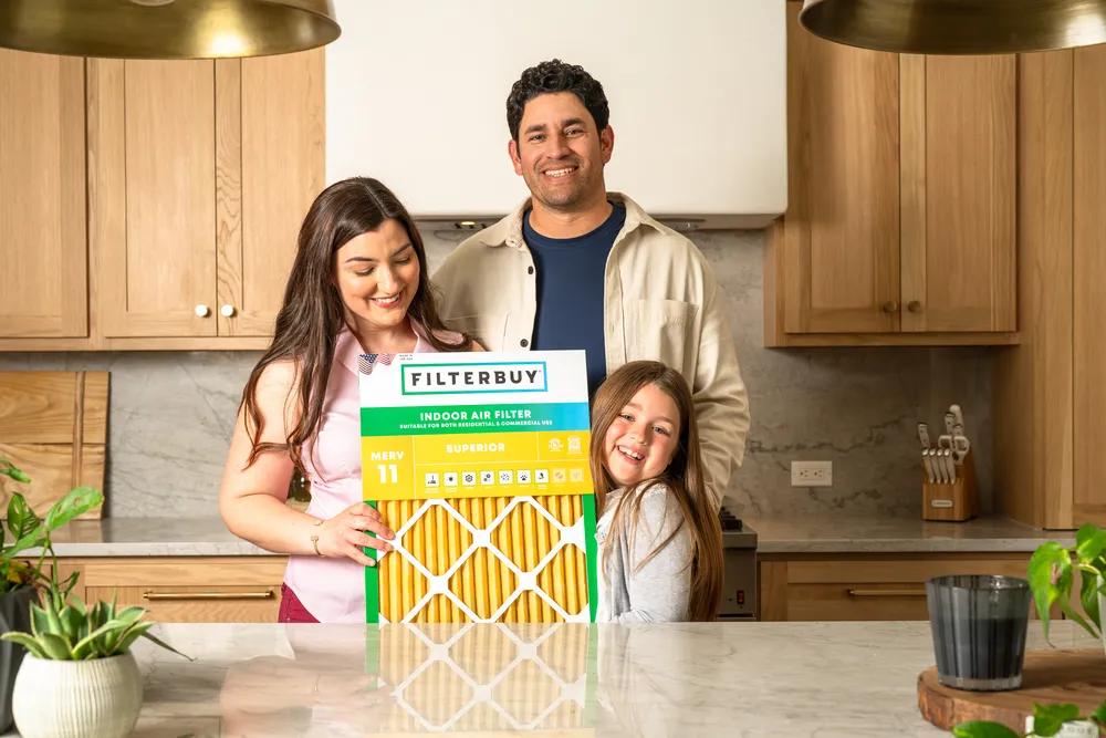 A view of a family in their kitchen holding a 17x17x4 air filter, representing top-quality HVAC and furnace filters for a healthier home.