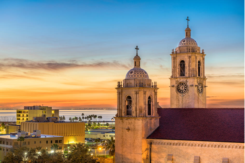 Urban skyline at dusk featuring illuminated high-rise buildings and colorful evening sky.