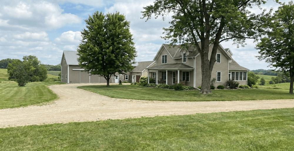 An image of a peaceful rural Wisconsin farmhouse and barn under a sunny sky.