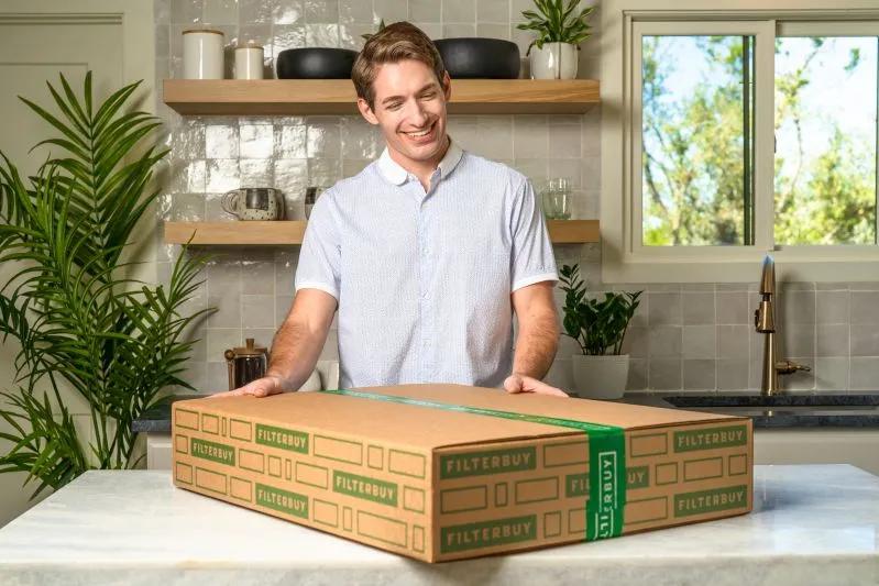 View of a man in a modern kitchen with a Filterbuy air filter package, ready to install for improved indoor air quality and allergen reduction