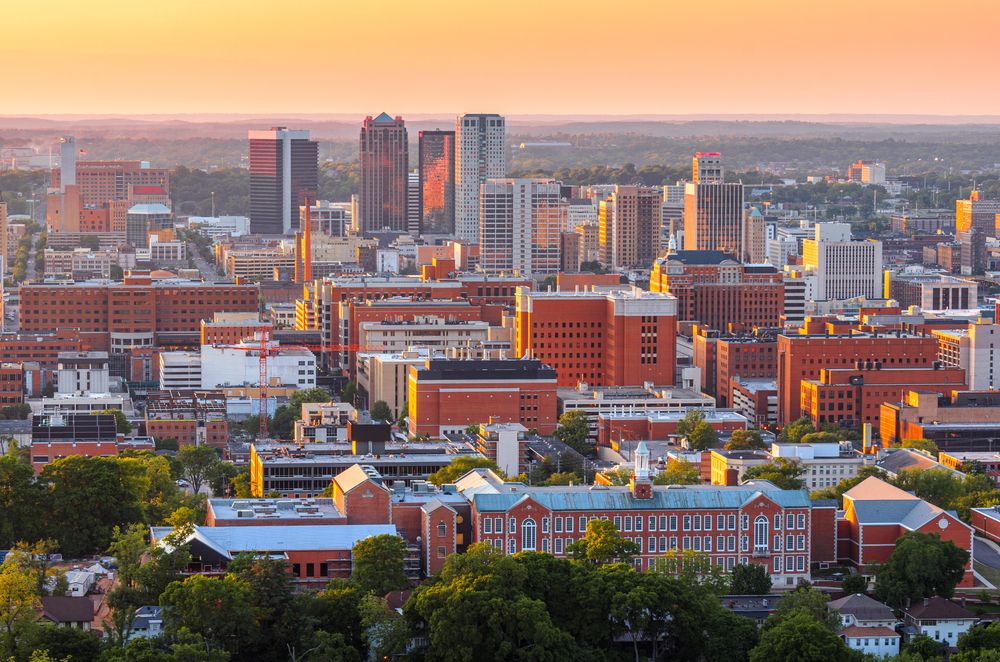 Birmingham, Alabama skyline during sunset with dense downtown buildings and glowing sky.