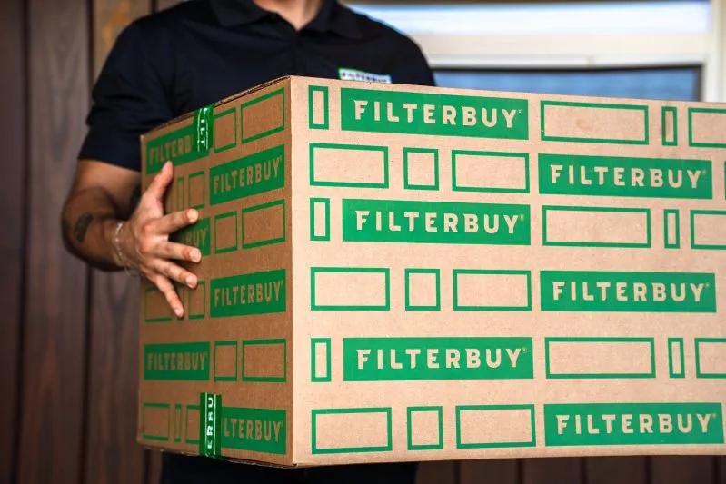 A view of a delivery person carrying a large Filterbuy box, highlighting fast and reliable shipping of HVAC air filters.