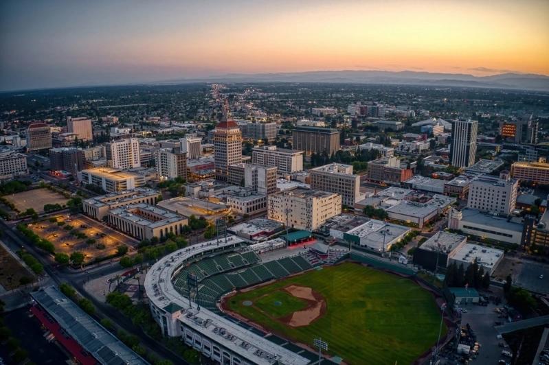 Cities With the Most Multigenerational Households - Image of Aerial view of Fresno, California, with downtown buildings and a baseball stadium at sunset, showcasing the city’s skyline.