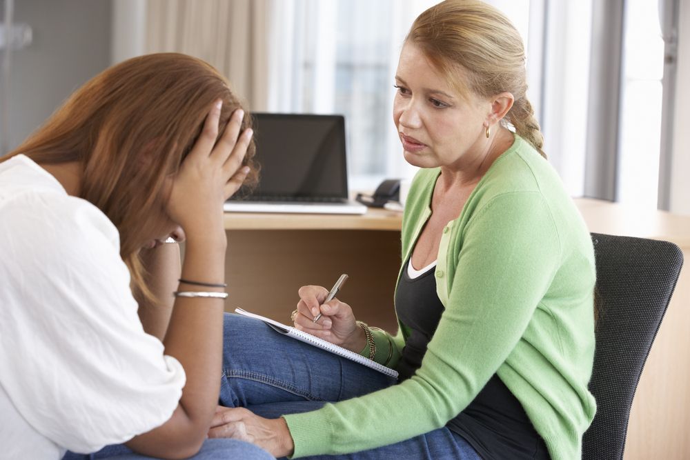 Counselor or therapist consoling a distressed woman in a therapy session