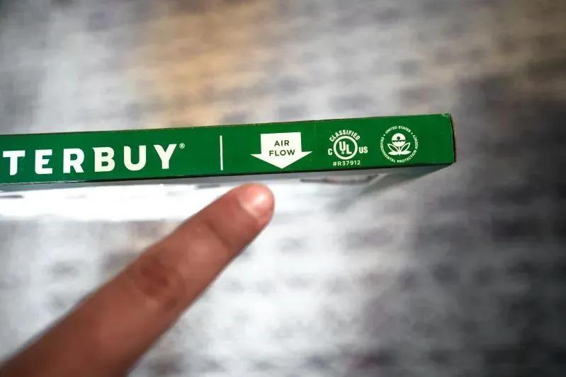 A view of a finger pointing at the air flow direction label on a Filterbuy air filter.