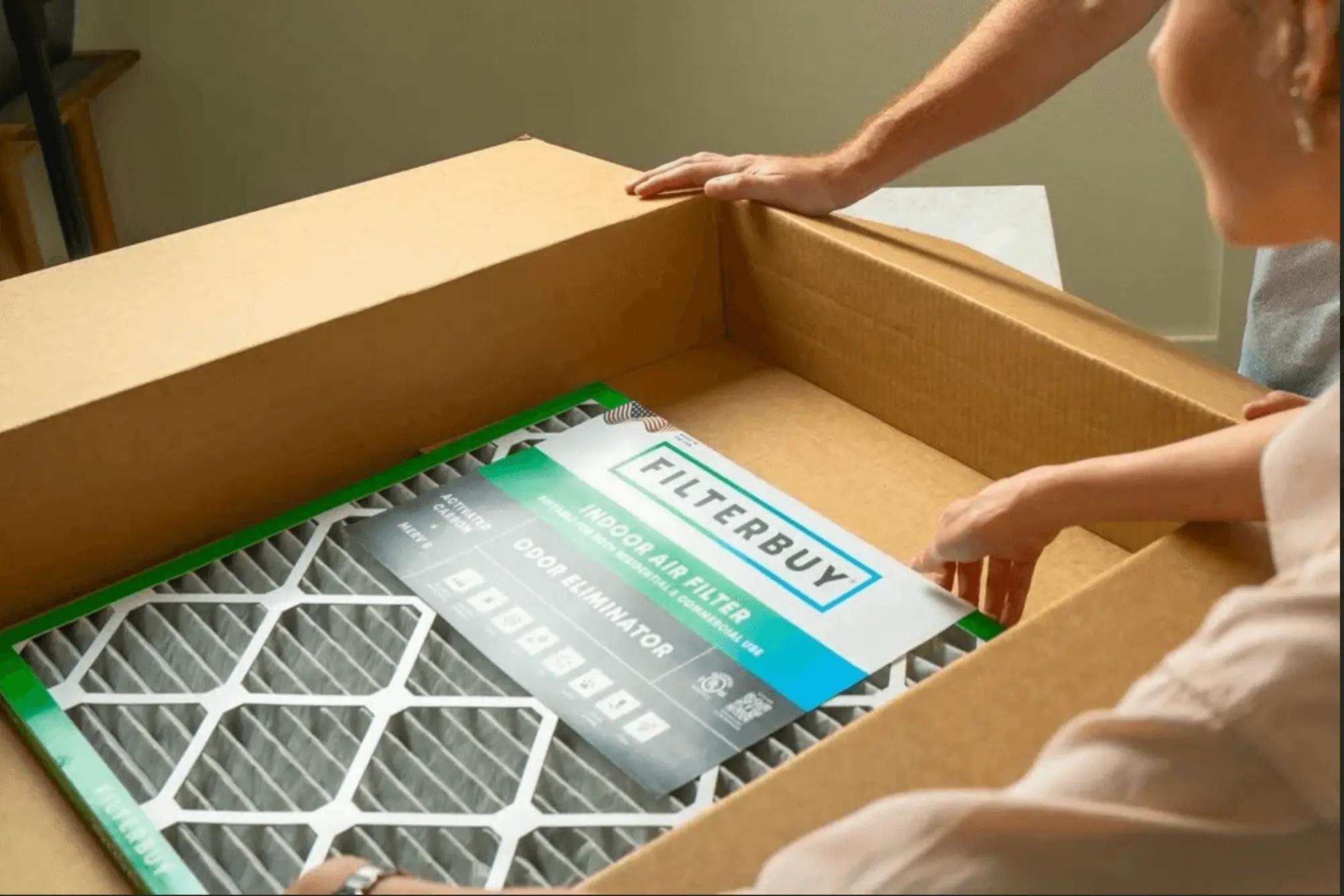 An image of hands opening a Filterbuy indoor air filter package, revealing the filter’s frame and product label.